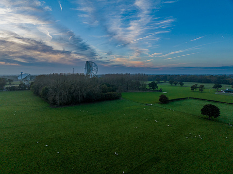 An aerial photograph of Jodrell Bank, Cheshire, England. The photograph was produced on a late autumn afternoon. The photograph shows autumnal trees overlooked by the Jodrell Bank telescope.