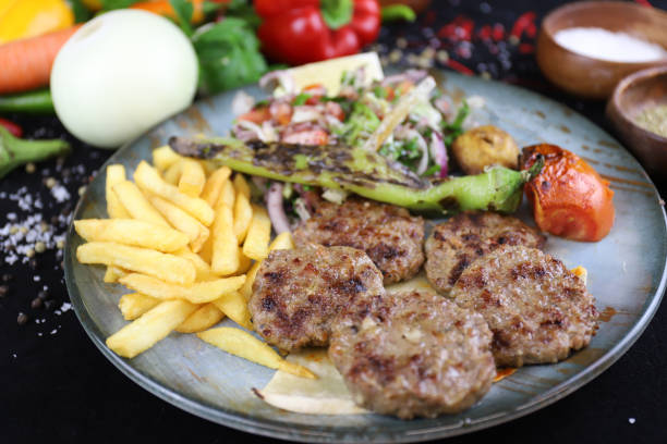 Grilled meatballs with fries and salad on a plate stock photo
