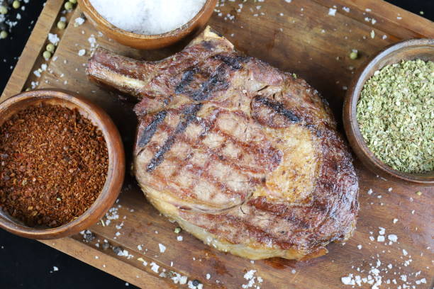 Grilled t-bone steak with spices on wooden cutting board stock photo