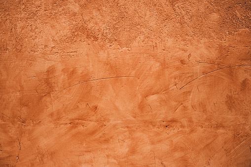 Terracotta colored plaster wall, rustic background or texture