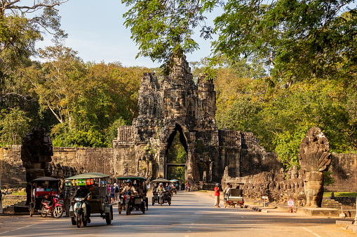 Angkor, Cambodia - Nov, 2019: Vehicle and tuk tuk traffic, passing through the southern gate that gives access to the Bayon temple grounds, in the ancient city of Angkor, Cambodia