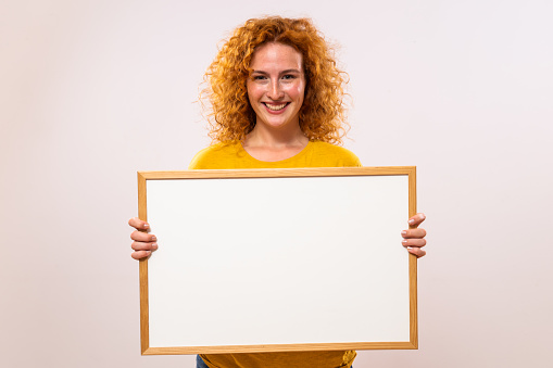 Beautiful ginger woman is holding white board.