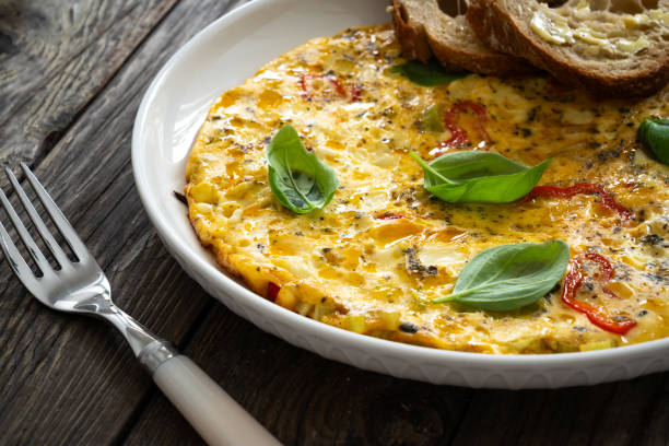 istock Omelette - scrambled eggs with cheese and vegetables on wooden table 1763101190
