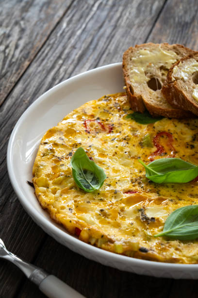 istock Omelette - scrambled eggs with cheese and vegetables on wooden table 1763101585