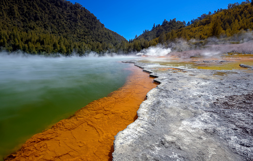 Colorful orange - green Champagne Pool in the Waiotapu Thermal Wonderland. The pool is a 65 m wide spring, containing multiple minerals that are presently depositing in the surrounding sinter ledge. Waiotapu, North Island, New Zealand.