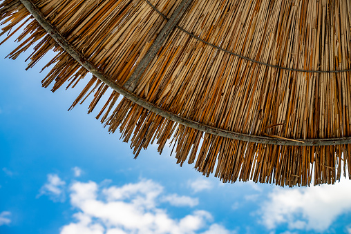 Sky with clouds under straw bamboo umbrella.