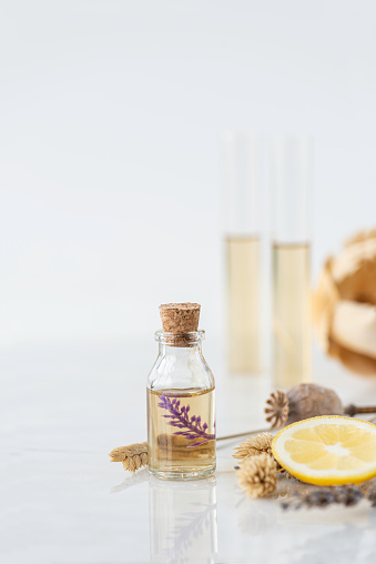 Front view of two bottles with dried lavender and herbs on marble background.