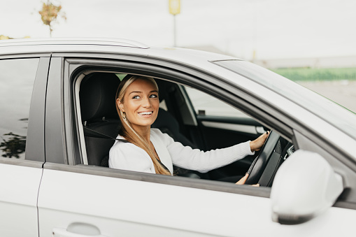 One young blonde woman driving a right hand steering car