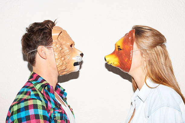 Facing off with animalistic intent Young hipster couple facing each other while wearing animal masks animal representation photos stock pictures, royalty-free photos & images