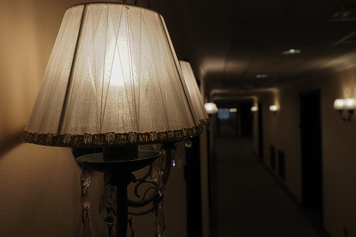 View of lamp on wall in hotel hallway. Dim light in dark hotel corridor. Background with space. for copying.