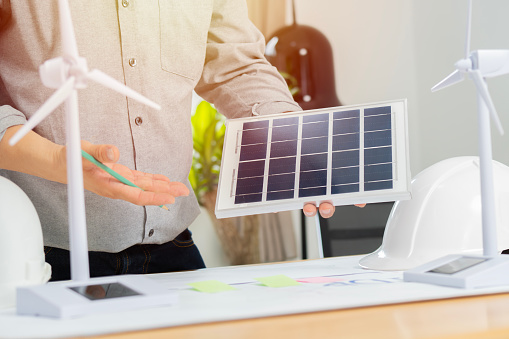 Engineers hold solar panels sample for testing efficiency of solar cell panels type in office. Solar and wind to output concept.