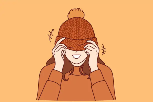 Vector illustration of Woman covers face with knitted hat with pompom and smiles standing in warm sweater