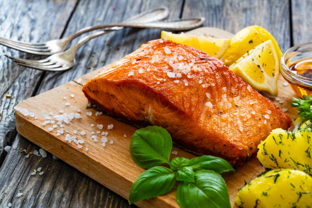 Seared salmon with boiled potatoes and fresh vegetables on wooden table
