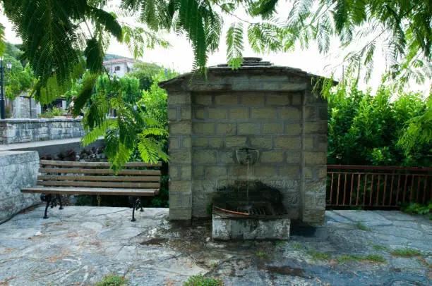 A stone fountainhead in Blacherna Arta, Epirus ,Greece with a bench