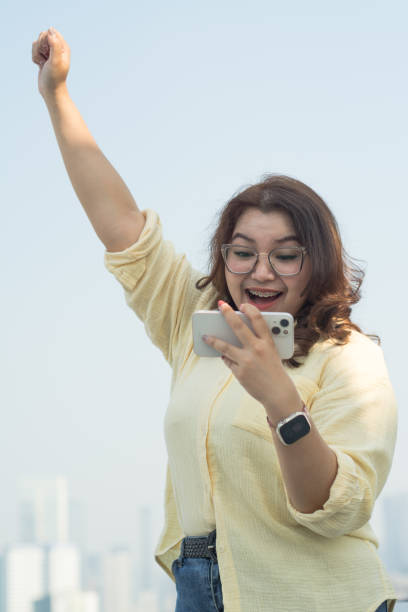 istock Asian Gen Z Woman Smiling While Using Smartphone in City Setting | Gen Z and Mobile Device 1763285401