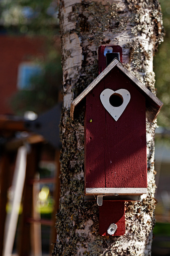 a red birdhouse with a white heart by the hole