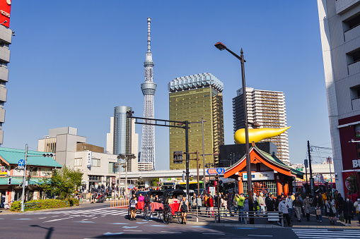Tokyo, Japan - April 09, 2023: street view from Asakusa to the Sumida skyline. To see are the famous Tokyo skytree and the Asahi Beer hall, with unidentified people on the street