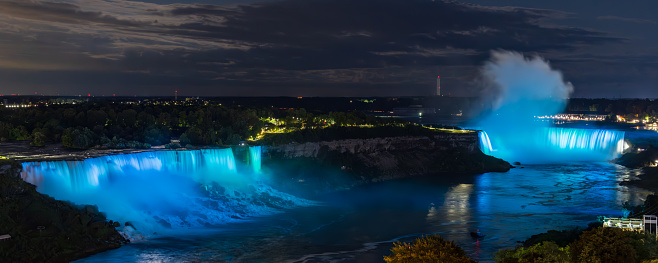 Blue illuminated American and Horseshoe falls at night in Niagara Falls, Canada