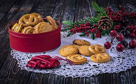 Cookies in a red box and on the table. Concept for National Cookie Day. Christmas branch and toy as decor on a wooden background.