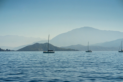 Sailing yachts against the backdrop of the blue sea and mountains melting into the air in the Mediterranean Sea on the Greek coast