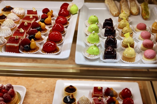 Pastry bakery store shop in Assisi, Umbria Italy selling dessert chocolate cannoli, rocciata cakes and pies with price tags through retail display glass window