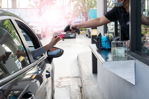 Contactless payment. Asian woman pay for food or drinks via smart phone using barcode reader scanning barcode by driving through or drive thru.