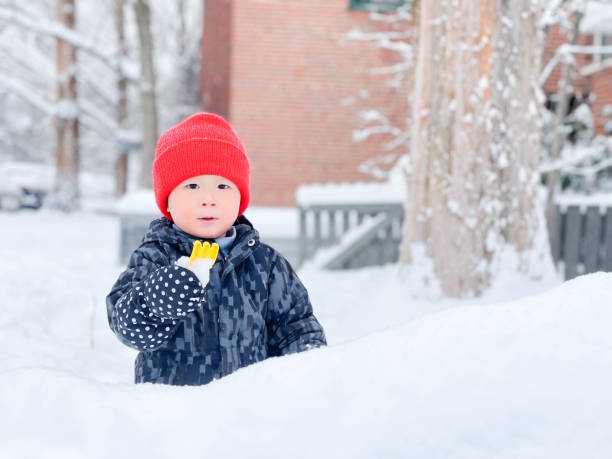 istock Cute little boy having fun and playing in playground during snowfall 1763340475