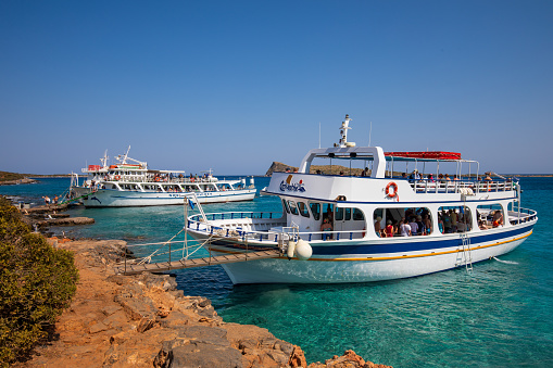 Kolokitha, Greece - September 3rd 2023: Large boats full of tourists exploring the clear waters and hot, dry coastline in Kolokitha, near Elounda, Crete