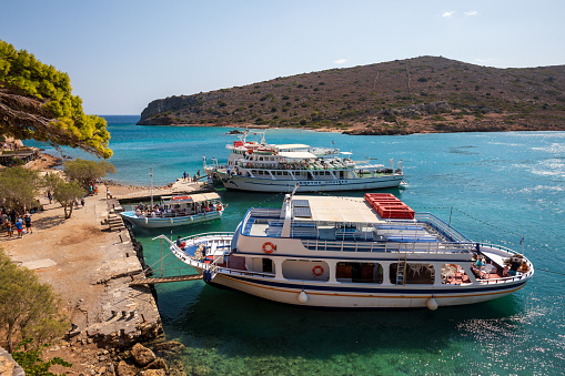 Kolokitha, Greece - September 3rd 2023: Large boats full of tourists exploring the clear waters and hot, dry coastline in Kolokitha, near Elounda, Crete