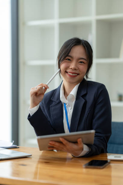 smiling asian business woman delight in the achievements by using the tablet to work with plans, ideas, ideas to present. financial report business plan investment new age concept online - news of the world imagens e fotografias de stock