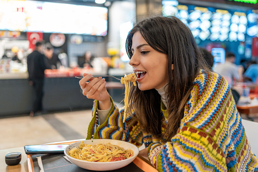 Young vegetarian woman eats spaghetti in restaurant