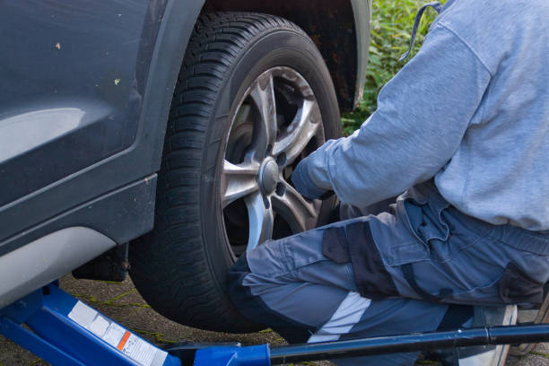 istock Mechanic fixes the wheel to the vehicle with his knees 1763349701