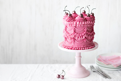 Pink celebration cake with vintage buttercream piped frills and cherries