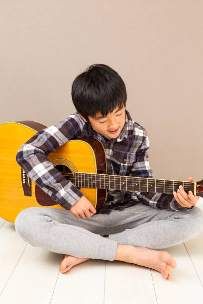 un garçon jouant de la guitare. - 12 13 years 13 14 years learning education photos et images de collection