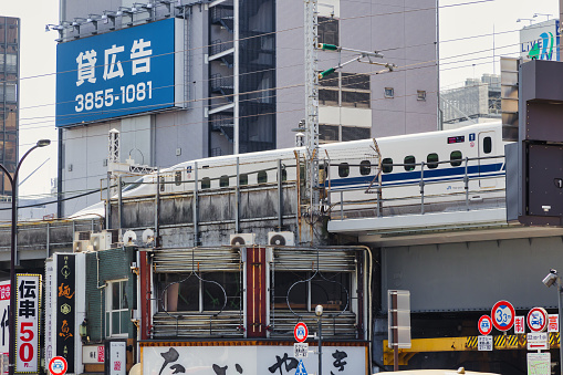 Tokyo, Japan - April 10, 2023: Shinkansen train on a railway line in downtown Minato. Shinkansen is a network of high-speed railway lines in Japan