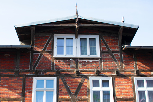 View of the building with brick walls, wooden inserts, small windows and a triple roof against the sky. Architecture in the German traditional style, half-timbered. Poland, Gdansk, April 2023