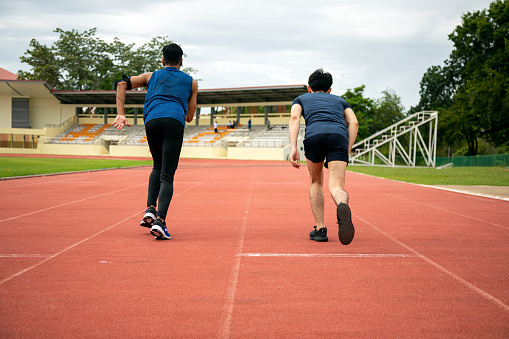 Two Asia male teenagers starting running in track for practice in Stadium