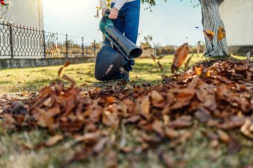 Man blowing leaves during autumn cleaning