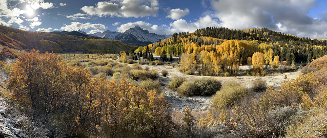 Rising to 14,150 feet in elevation, a light snow covers Mount Sneffels with autumn yellow aspen and willows in the Uncompahgre National Forest, Ridgway, Colorado.