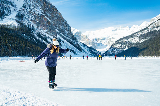 Lake Louise, Alberta, Canada - March 17, 2023: Tourists cautiously ice skating on the frozen lake in Banff National Park.