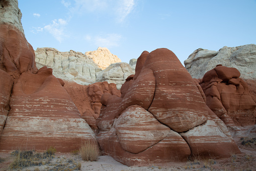 A stunning canyon filled with sand and sandstone rock formations that have red and white layered rocks.
