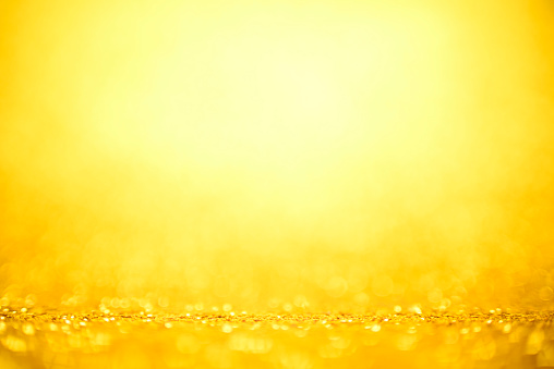 Defocused golden sequin light. Studio shooting of a creative bright yellow color background. It is textured color gradient. There are no text and no people, and have copy space for design. It’s Suitable for commercial use. Christmas, New Year, Diwali festive celebrations themed backgrounds, wallpapers, templates for greeting cards, banners and posters and wrapping paper is apt.