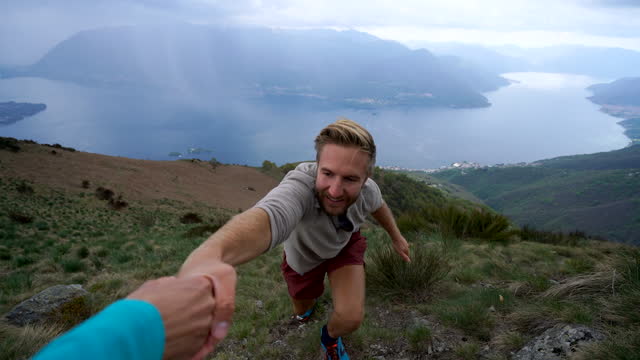 A helping hand, Man hiker reaches mountain top, hand pov reaches out to help