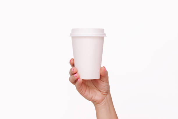 istock Woman's hand holding white eco paper cup with white lid with tea or coffee. Mockup with copy space 1763440343