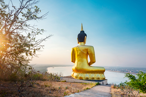 Famous hilltop landmark,a beautiful, vibrant gold image of the Buddhist icon,reflecting light from the setting sun,popular holy site and tourist attraction overlooking Pakse,and river below.