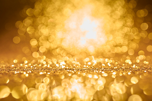 Defocused golden sequin light. Studio shooting of a creative bright yellow color background. It is textured color gradient. There are no text and no people, and have copy space for design. Its Suitable for commercial use. Christmas, New Year, Diwali festive celebrations themed backgrounds, wallpapers, templates for greeting cards, banners and posters and wrapping paper is apt.