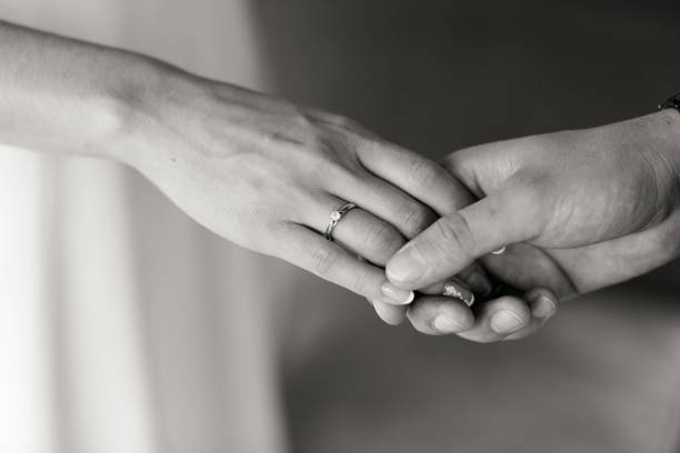 istock Close-up monochrome shot of hands intertwined with an engagement ring highlighting commitment. 1763456263