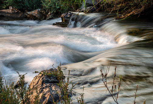 River water details,at sunset.Sunlight shining on rocks,next to blurred movement of water,rushing by,at the main waterfalls and rapids of Don Khon island.