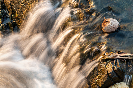 Abstract details of water movemet,at sunset.Sunlight shining on rocks,next to blurred motion of the river,rushing by,at the main waterfalls and rapids of Don Khon island.