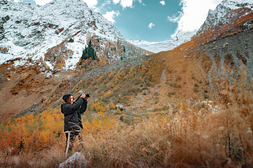 Woman traveler making photo of landscape mountains with camera, Female hands holding camera and doing nature photography while enjoying beautiful autumn nature landscape wanderlust